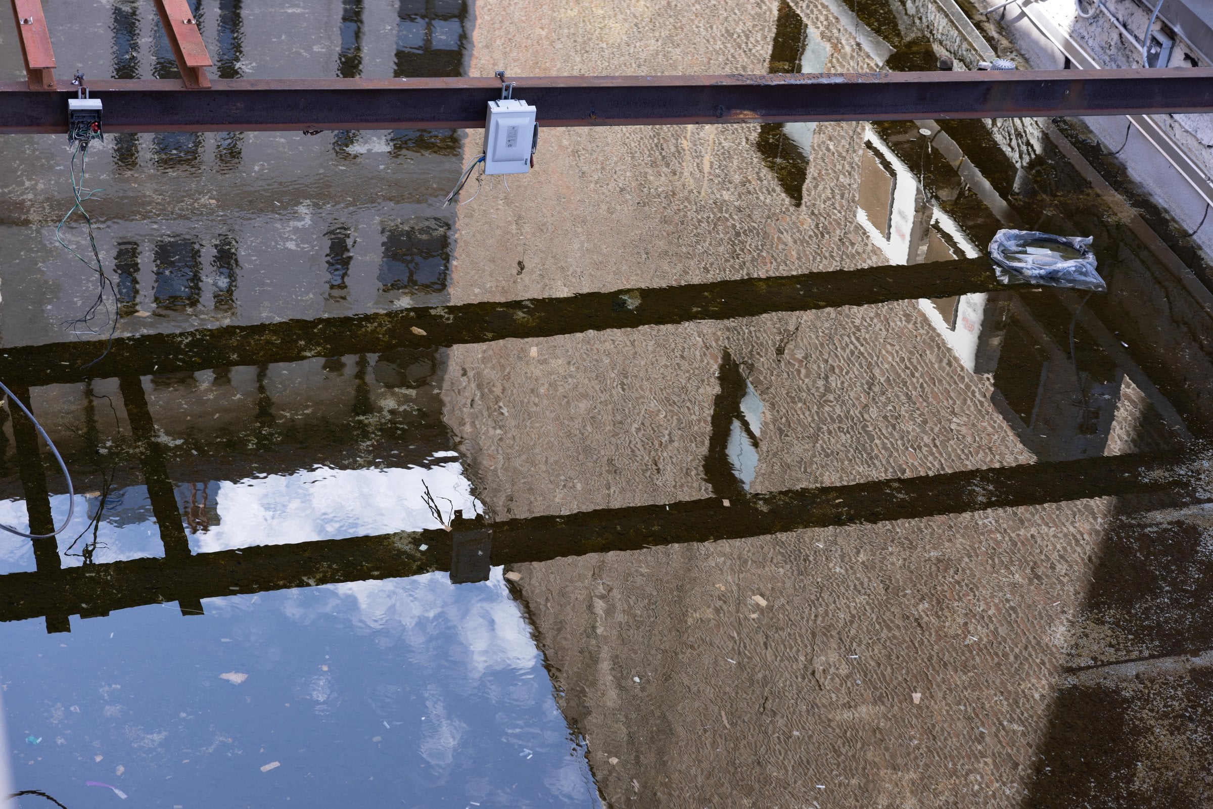 Steel beams and buildings reflected in standing water