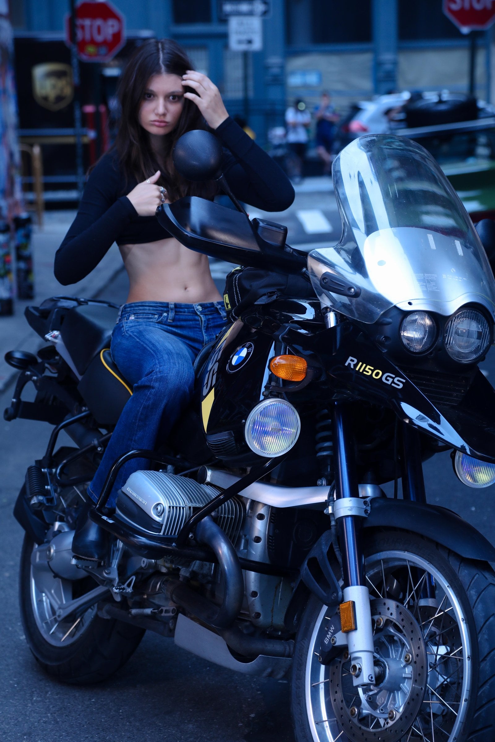 Person in a black top and jeans sitting on a motorcycle