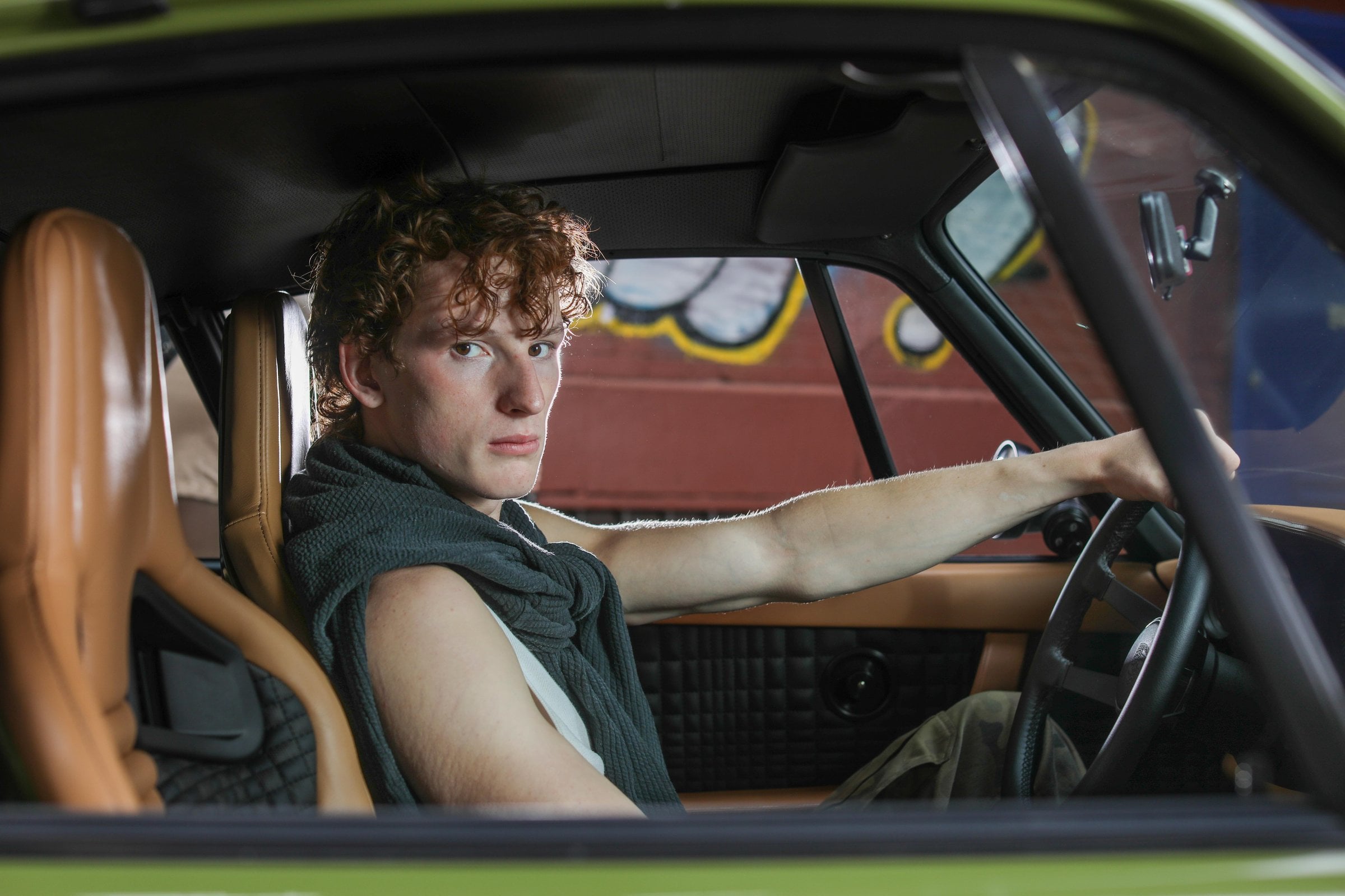 Person with curly hair holding the steering wheel inside a car