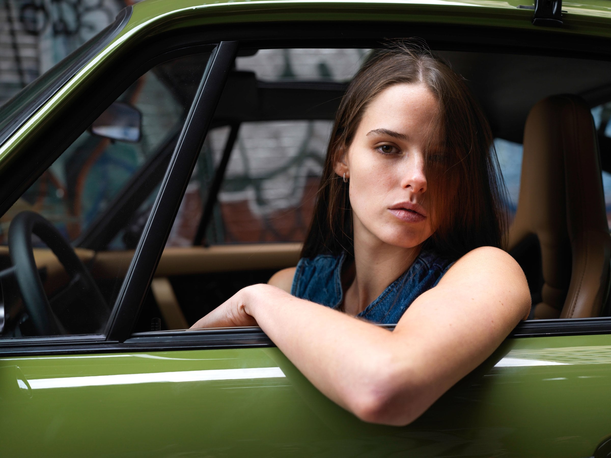Person resting an arm on the window of a green car