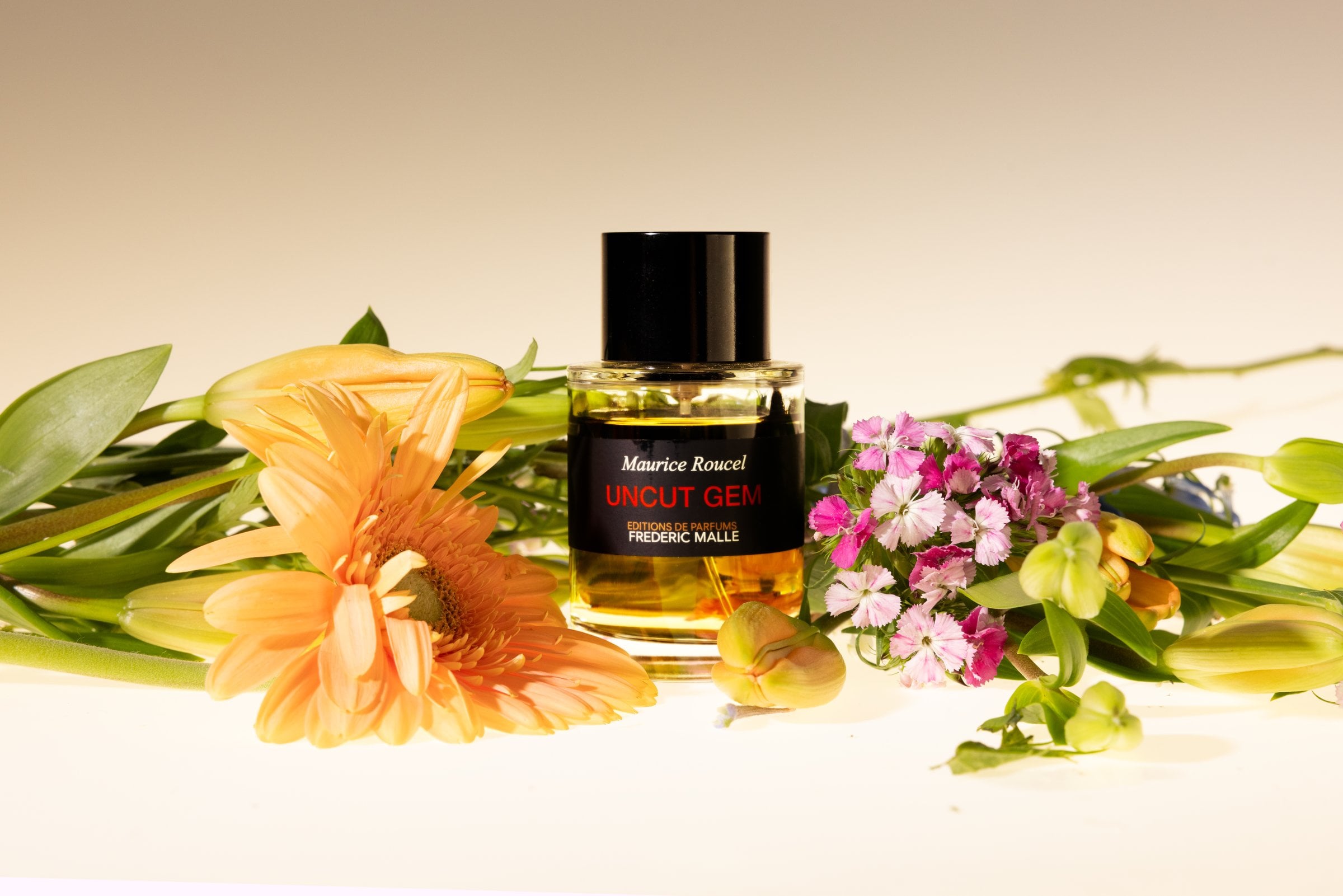 Perfume bottle surrounded by orange and pink flowers