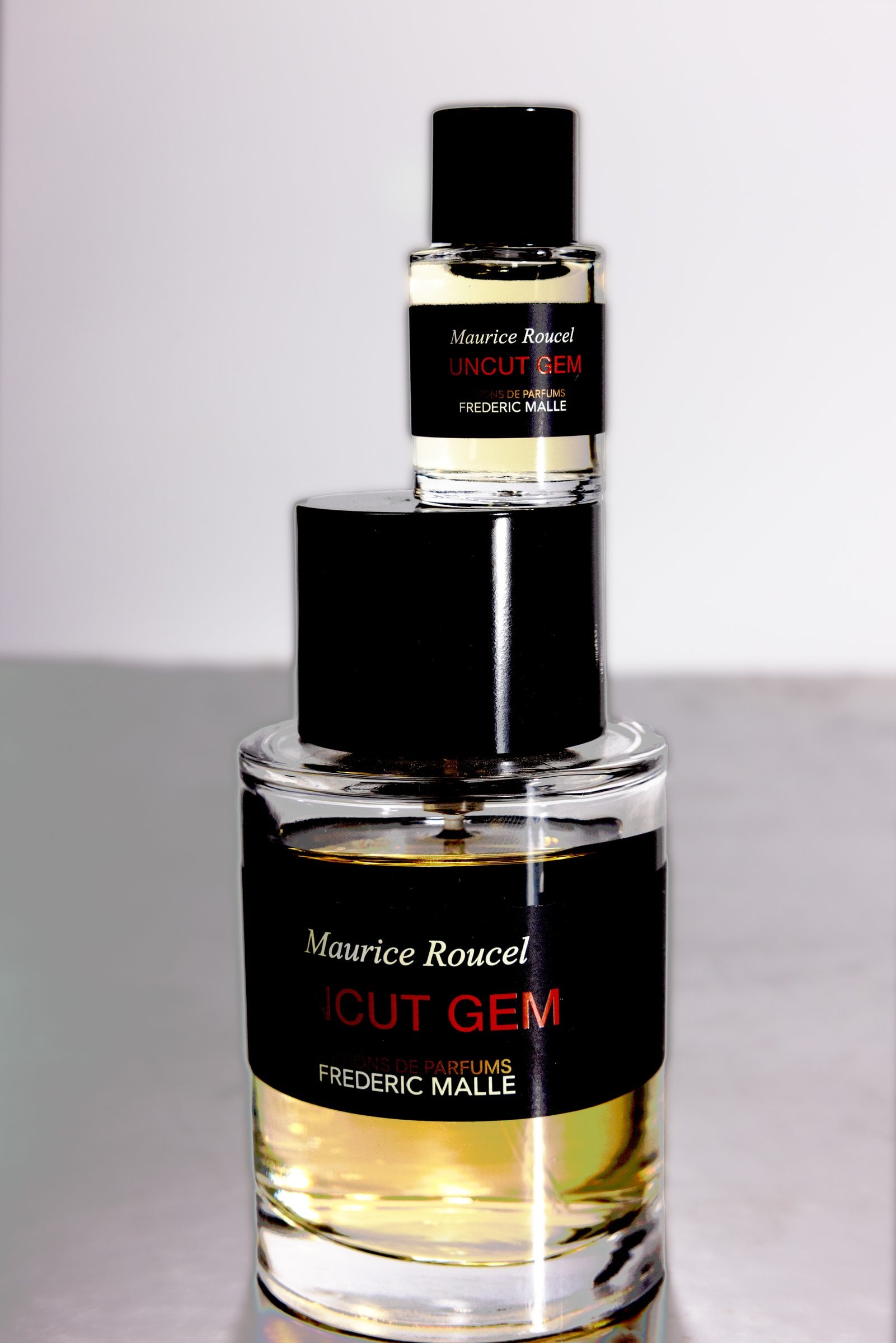 Small perfume bottle stacked on a larger bottle with black caps