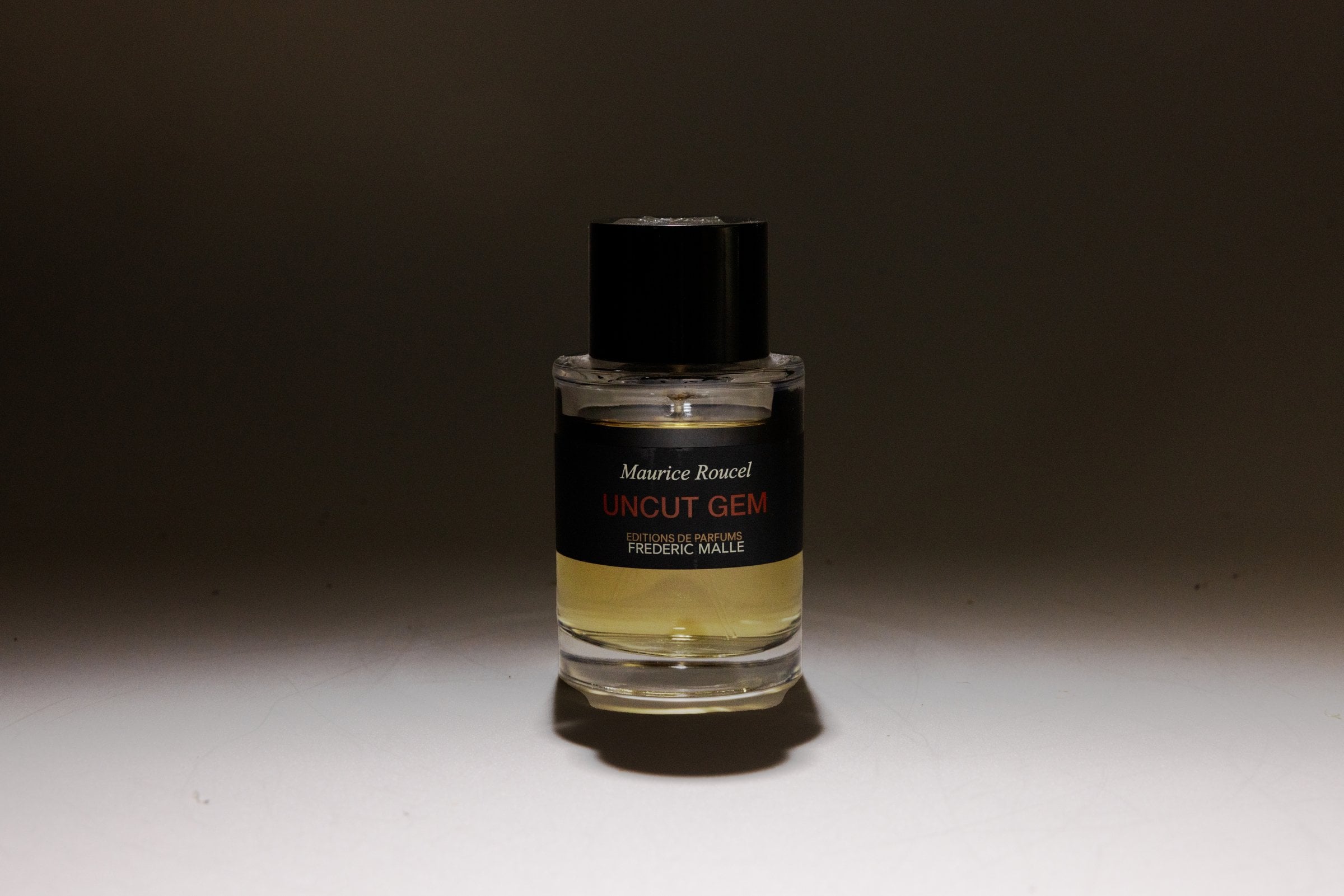Perfume bottle casting a shadow under a narrow pool of light