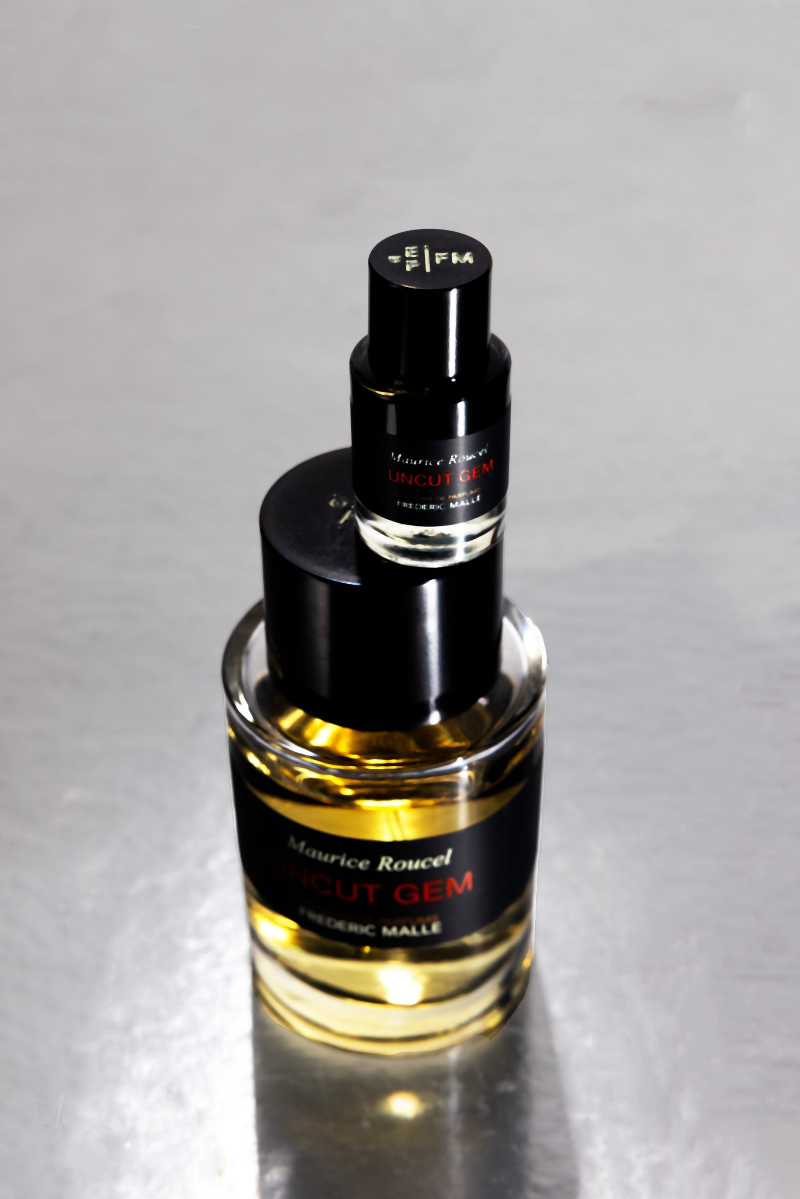 Two perfume bottles stacked vertically, viewed from above
