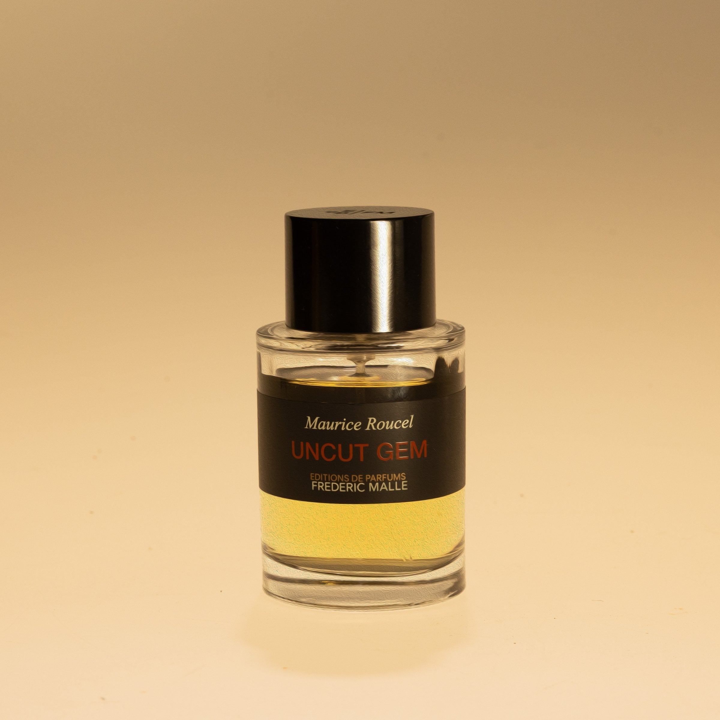 Glass perfume bottle with a black cap against warm yellow light