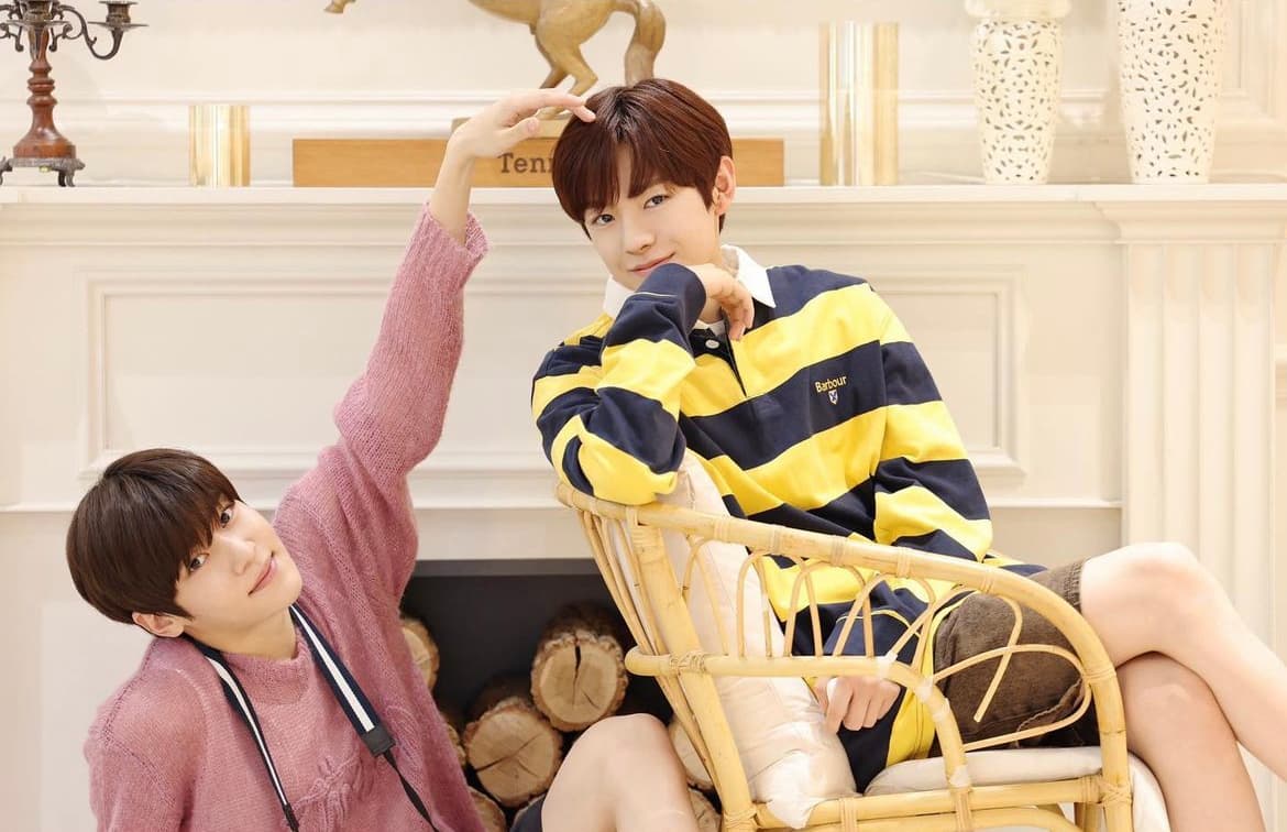 Two people posing beside a fireplace